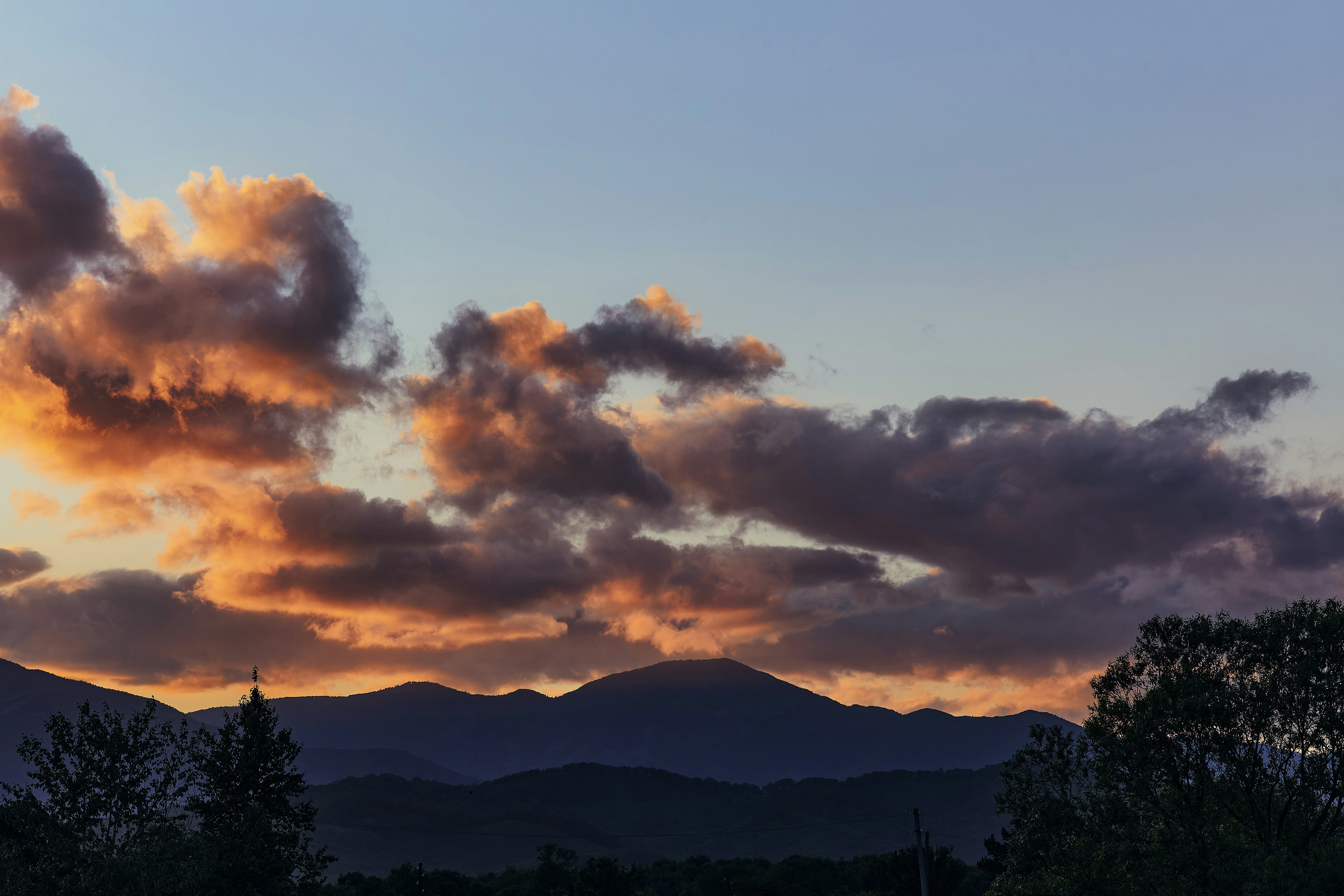 silhouette of mountain under cloudy sky during sunset